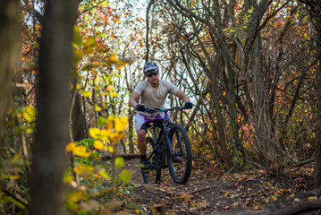 A mountain biker rides a challenging trail through the forest.