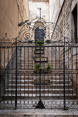 Schmiedeeisernes Tor, dahinter Stein Blumenkübel auf einem Treppenaufgang zu einer Kirche in Figueras, Spanien