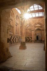 Vertical shot of sun shining through historical Arabian palace interior with arcs and columns