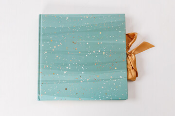 closed beautiful turquoise photo album with a bow on a white background