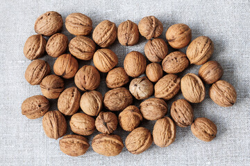walnuts in shell on gray linen fabric close-up.