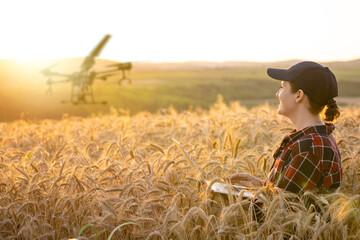 Woman farmer controls drone sprayer with a tablet. Smart farming and precision agriculture.