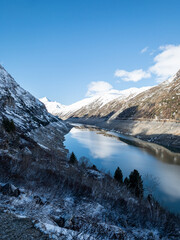 Valley of Lei. Swiss. Dam. Mountain Dam Under Blue Skies. A dam with a road atop, nestled between...