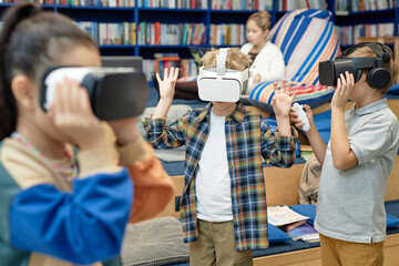 Group of young kids wearing VR headsets in school library and enjoying immersive learning experience