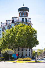 A beautiful view of a church behind residential buldings and tree branches - Madrid, Spain