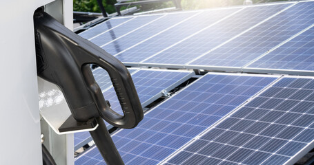 Close up of electric car charging station on the background of solar panels..