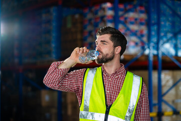 A man in a yellow vest is drinking water. Concept of staying hydrated while working in a warehouse