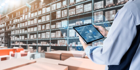 Business Logistics warehouse management system technology concept.Man hands using tablet on blurred warehouse as background