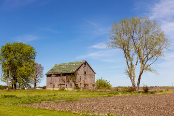 Obraz premium Field with old farm and blue sky