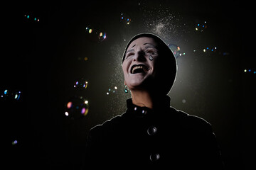 Minimal portrait of excited mime artist standing in soap bubbles on stage, copy space