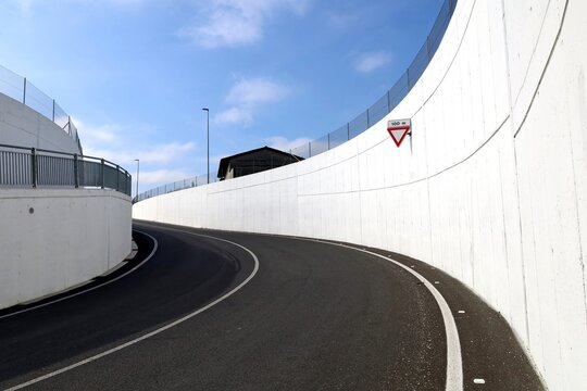 Yield sign on white concrete wall in the  road curve at the exit an underpass. Background for copy space.