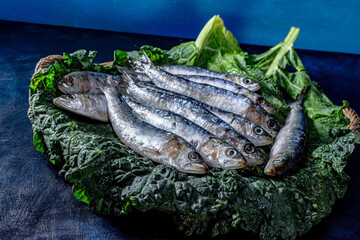 A basket with fresh sardines on top of greens