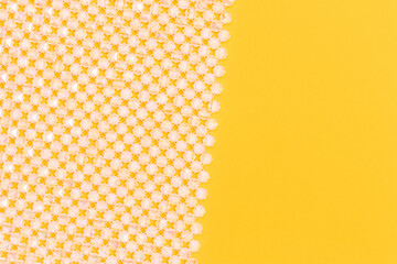 Detail for handmade bag made from shiny acrylic beads on a yellow background. Place for text.