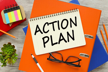 Action Plan Top view of empty notepad and various office supplies on wooden table