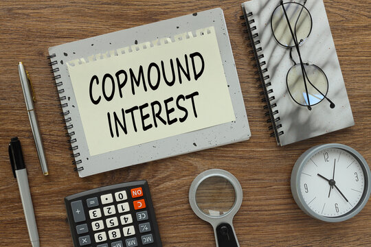 Compound Interest gray notepad with text on a torn page. a table clock