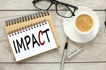 glasses and a cup of coffee on the work table. text IMPACT
