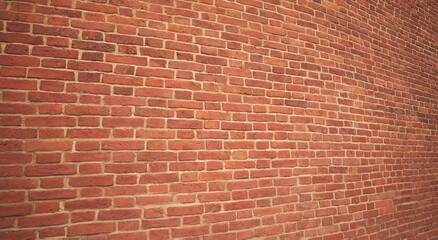 The wall is made of dark red brick. The texture of the dark brown and red brick wall creates a panoramic background.