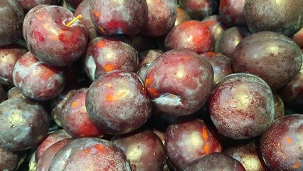 Close up pile of tasty fresh plums sold at the market as a background.