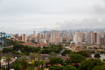 Obraz premium A view of Benidorm from Mundomar on a wet rainy day, Image shows the beautiful holiday resort covered by dark grey clouds and heavy downpour just before the start of the holiday season