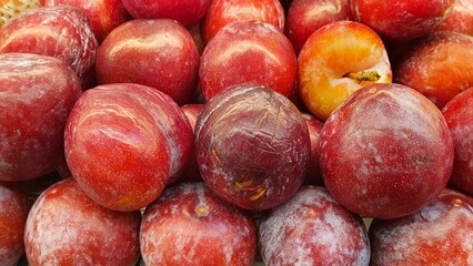 Close up pile of tasty fresh plums sold at the market as a background.