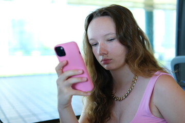 A thoughtful beautiful girl travels on a train, subway and uses a smartphone. Vancouver Canada. Travel, transport and technology concept
