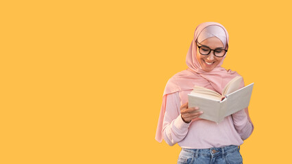 Book lover. Learning hobby. Happy smiling smart woman in headscarf glasses enjoying reading fun novel isolated on orange empty space background.