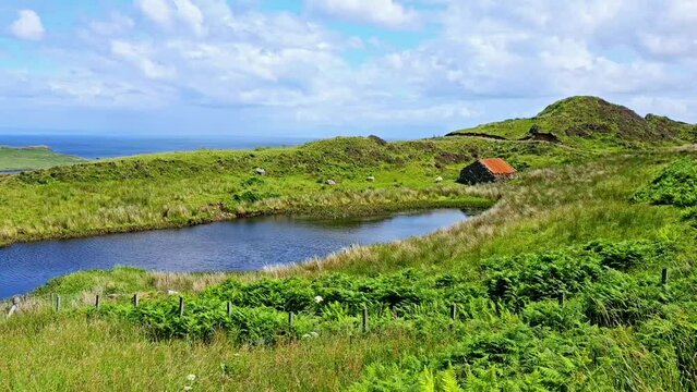 Isle of Skye, Scotland. Old stone cottage beside a small lake along the beautiful coast. Handheld panning motion.