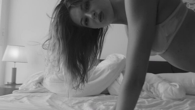 Woman in underwear moving sensually on bed