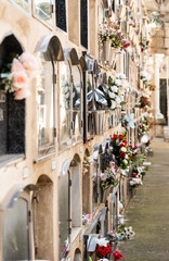 Blumenvasen an einer Wand aus Gräbern auf einem Friedhof in Barcelona, Spanien
