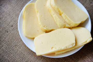 Slices of cheese cut on a plate. Delicious cheese with holes.