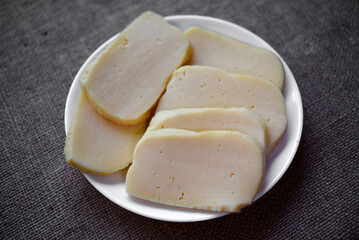 Slices of cheese cut on a plate. Delicious cheese with holes.
