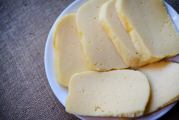 Slices of cheese cut on a plate. Delicious cheese with holes.
