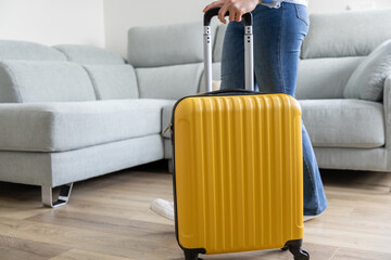 girl leaving home with her yellow wheeled suitcase to go on a family trip