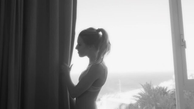 Woman in underwear walking in a hotel and hiding behind curtain