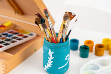 Art brushes, an easel with watercolors and gouache. A place for the artist's creativity. Selected...