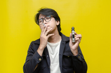 young Asian man holding a cigarette and e-cigarette vaping device. quitting smoke concept. smoking...