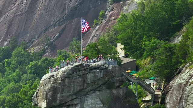 Chimney Rock with flattering American national flag and many tourists at Chimney Rock State Park in North Carolina, USA. Travel destination spot in Appalachian mountains