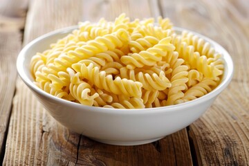 A closeup of a white bowl filled with perfectly cooked fusilli pasta on a wooden table