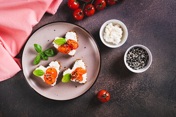 Appetizing crostini on rye bread in the shape of a heart with ricotta and tomatoes top view