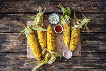 Grilled corn cobs with sauce, coriander and paprika
