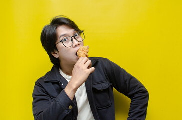 Asian man holding fried chicken stickdrum with expression of satisfication. 