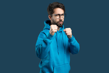 A man wearing a blue hoodie is shown with his fist raised in the air, showcasing a gesture of...