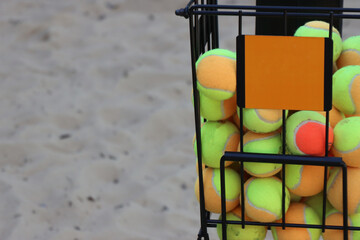 Beach tennis ball cart in the sand full of balls. Close up in the balls 