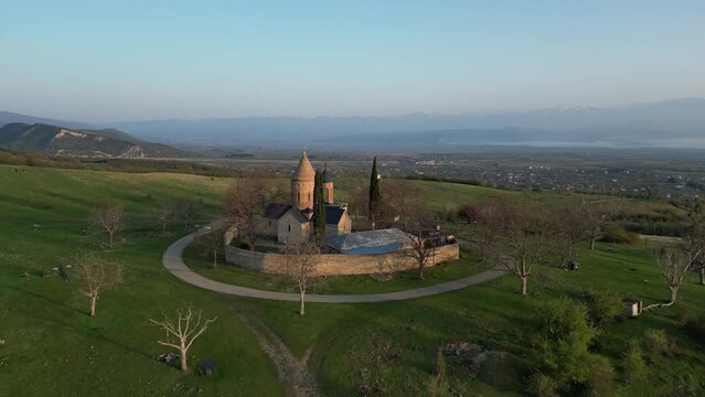 lonely ancient church in the mountains at dawn between green hills, aerial view