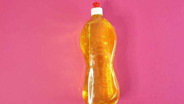 Hand pulls out a bottle of dishwashing detergent. Person in a blue rubber glove pushes a bottle with yellow liquid. Cleaning Services Concept. Template with copy space on the left