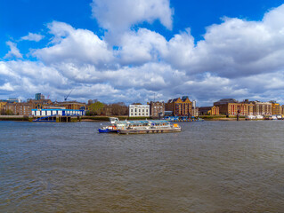 Tourist boat transporting passengers and tourists, anchored with a chain and the London docks seen...