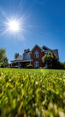 A sun-drenched brick house with a well-manicured lawn, captured from a low angle with a dramatic sun starburst in the blue sky