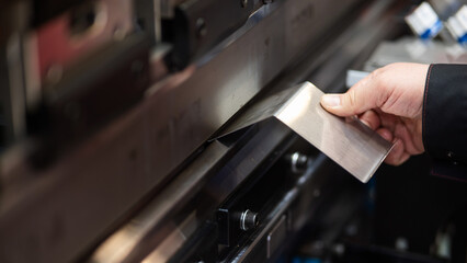 A master bends metal sheets on a machine. Hydraulic Press. 