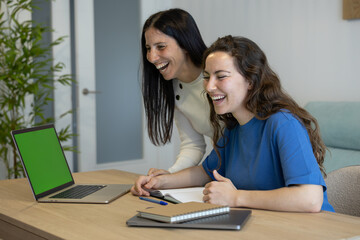 girls laughing together while working from home with the laptop
