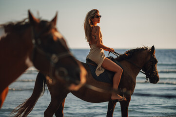 Tattooed beautiful young woman horseback riding on a beach